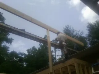 Carpenter setting a ridge beam over a new addition frame — Ice Dam Removal by Roofing Brothers in Suncook