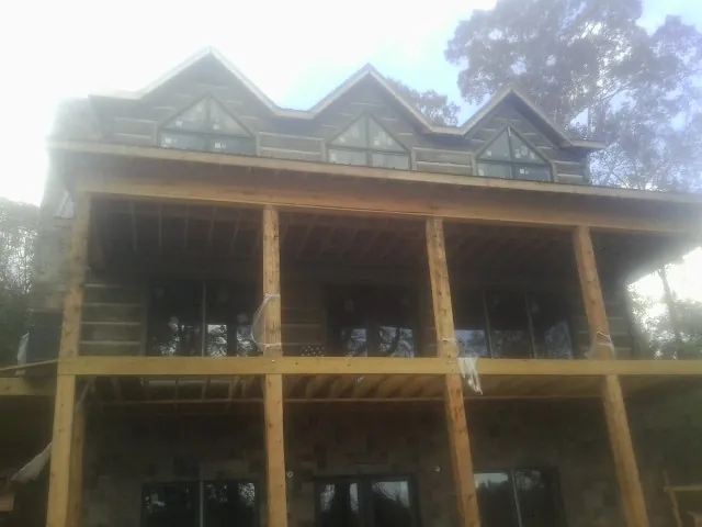Dormers and porch framing on a large log home under construction — Roof Coating work by our crew in Suncook