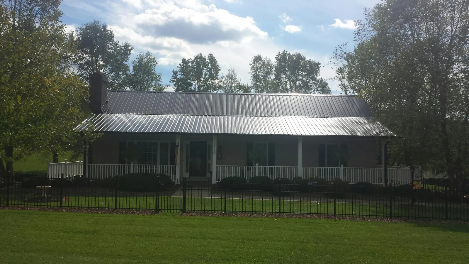 Gray metal roof on a brick ranch with a full width front porch — Gutter Guard Installation work by our crew in Suncook