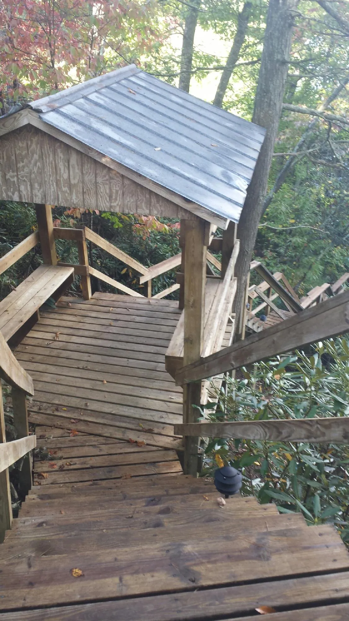 Metal roofed shelter over wooden steps on a wooded walkway — Skylight Repair & Installation work by our crew in Suncook