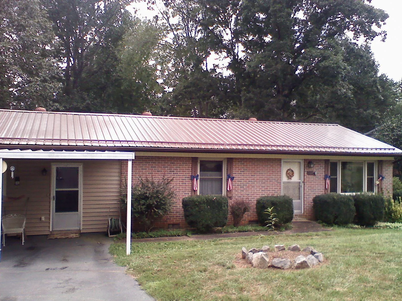 Bronze metal roof and carport on a brick ranch home — Roof Repair work by our crew in Suncook